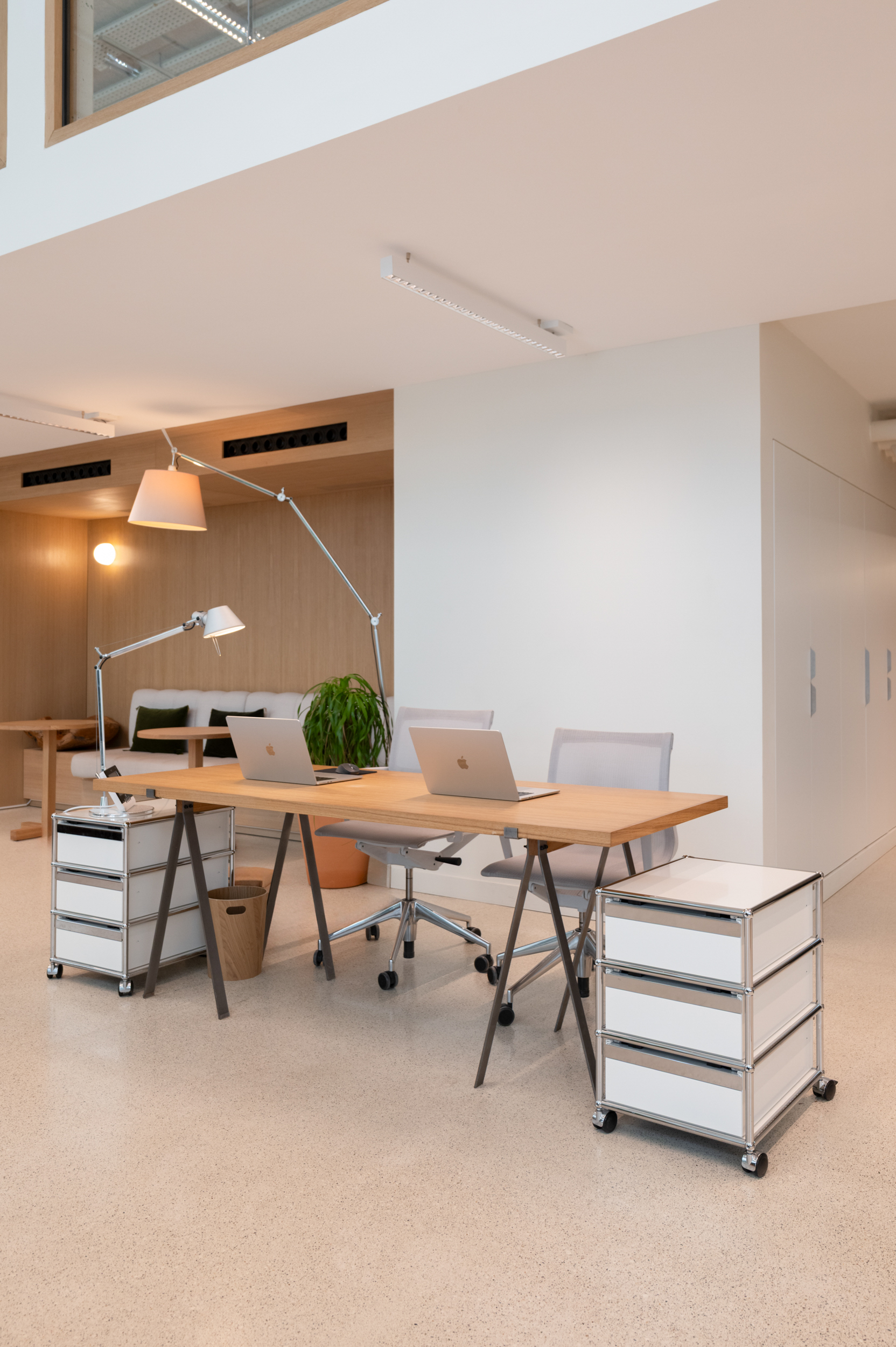 Modern office space with a wooden desk, chairs, and storage drawers.