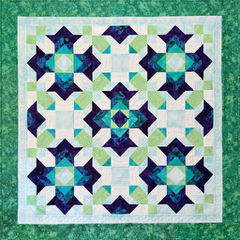 Colorful quilt with geometric star patterns in green and blue.