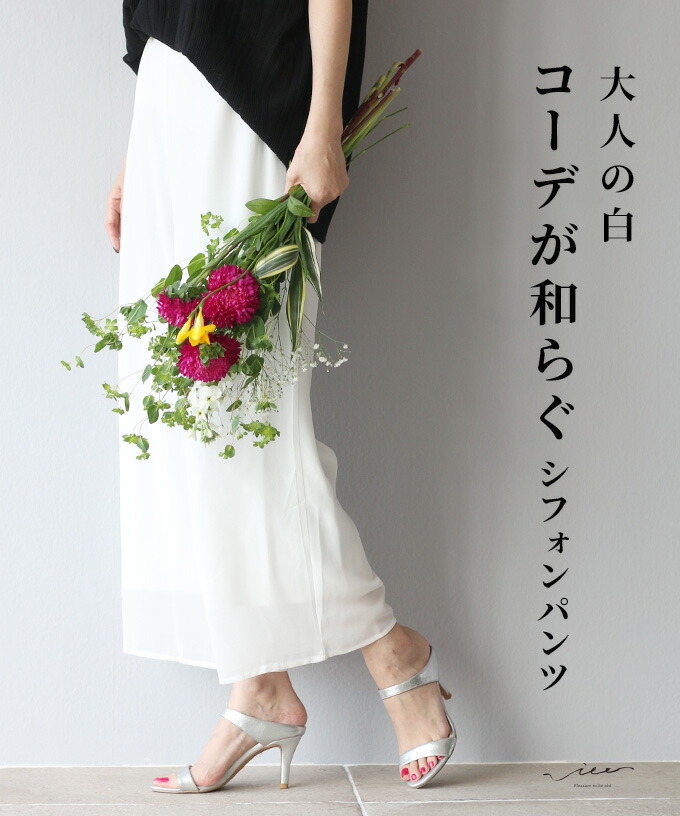 A woman holding flowers, wearing a white skirt and silver heels.