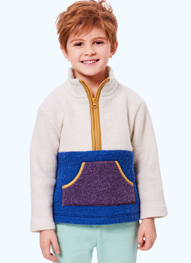 Smiling child wearing a colorful fleece pullover with a zip collar.