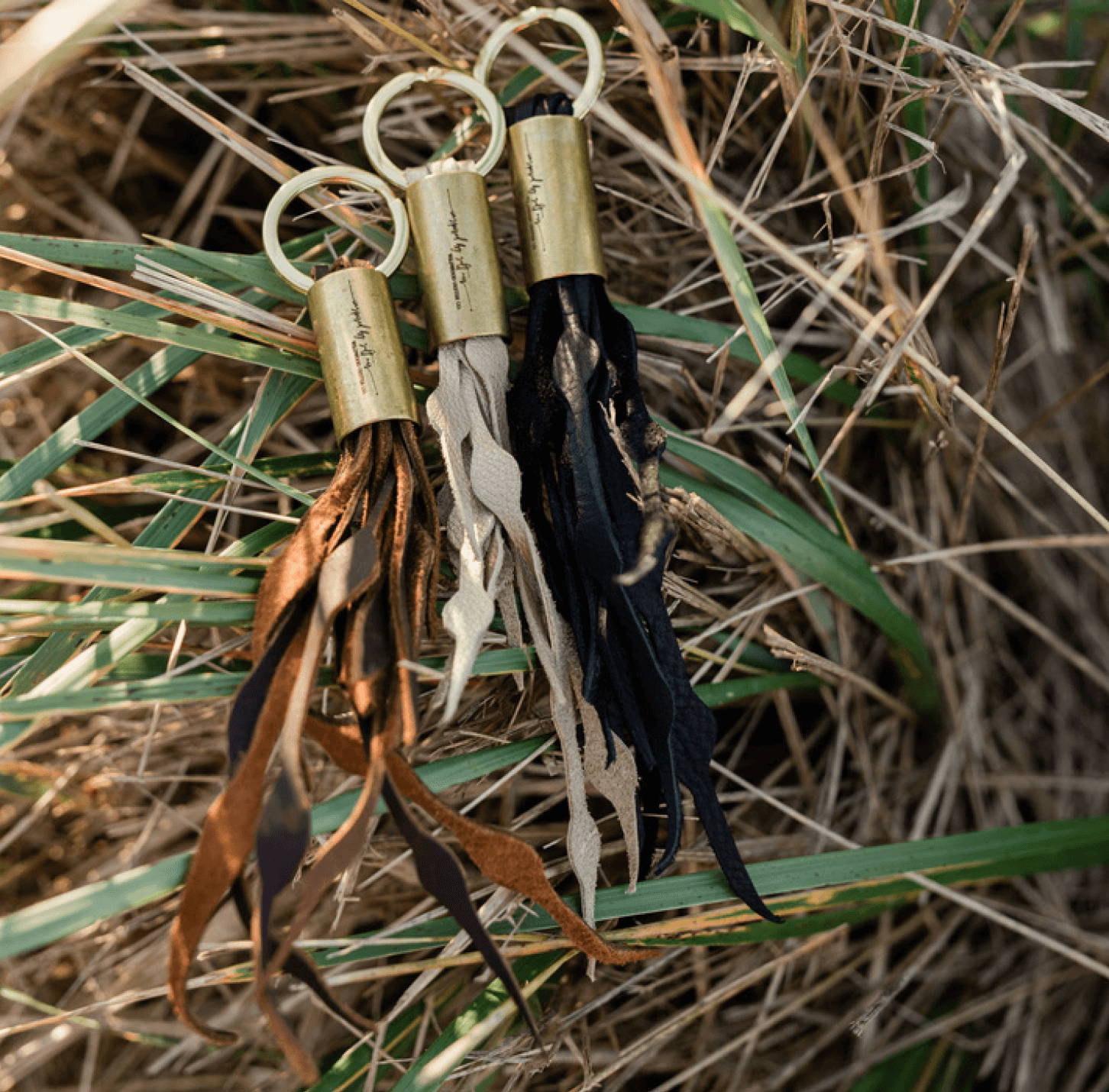 brown gold and black leather keychains on the beach grass