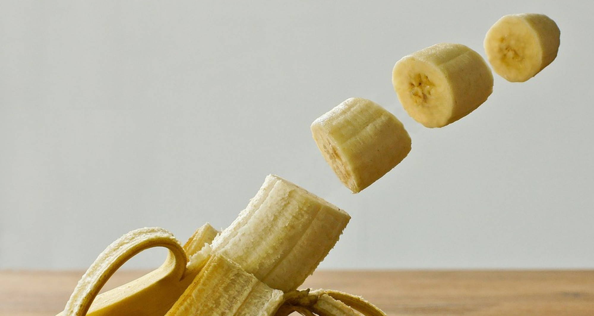  a banana with three cut pieces suspended in the air above