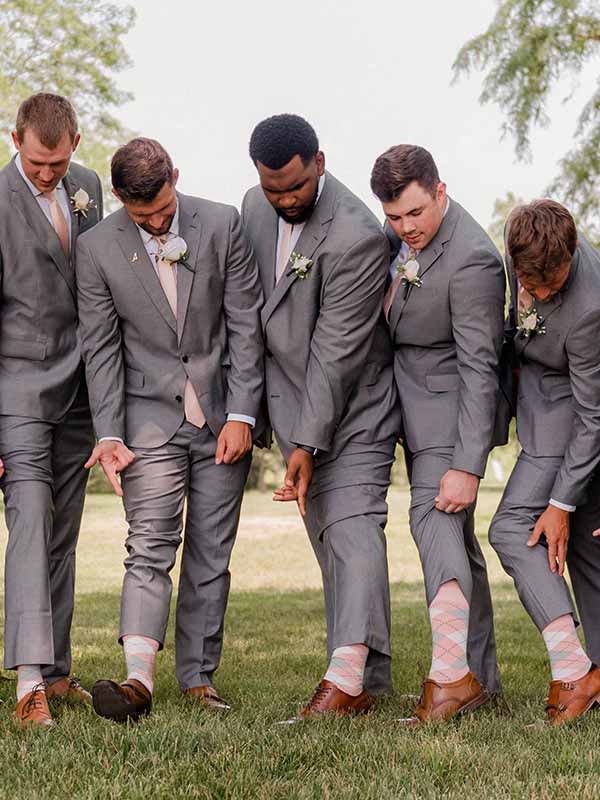 Groom and groomsmen pulling up their pants to show off their blush pink socks