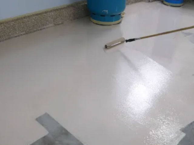 Spreading thin, even coat of Moisture Seal Epoxy Primer on floor using a magic trowel squeegee and microfiber roller.