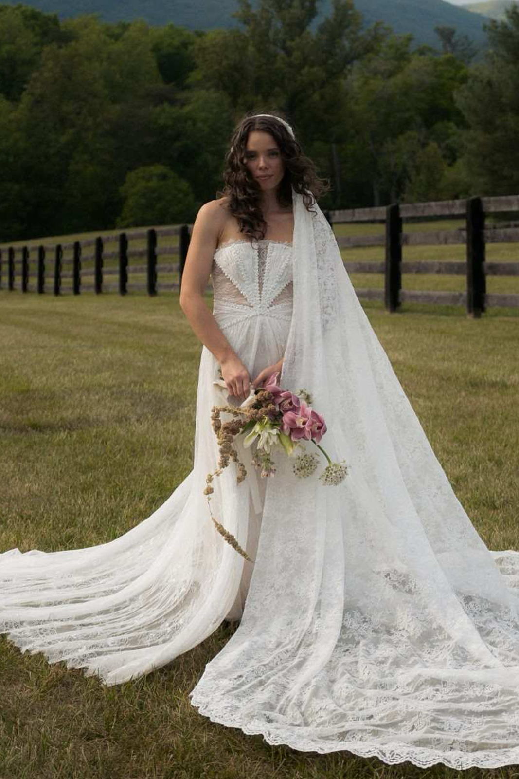 Bride in a white wedding dress holding flowers in a natural setting.