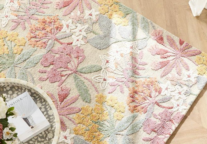 Colorful floral patterned rug on wooden floor with decorative tray.