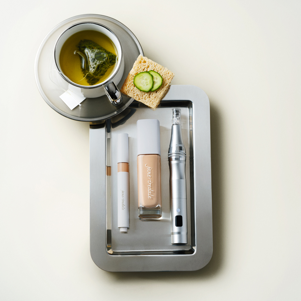 Tea, skincare products, and cucumber slices on a tray.