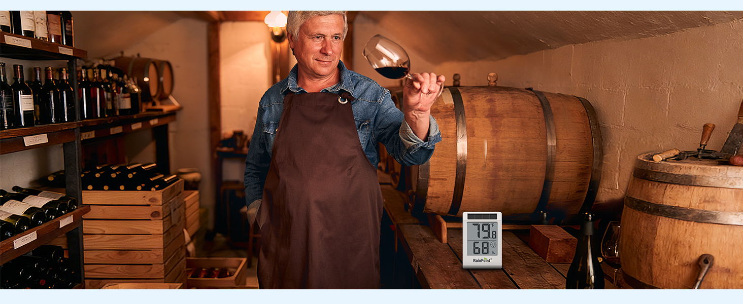 Man in apron holding a glass of wine in a cellar with barrels.