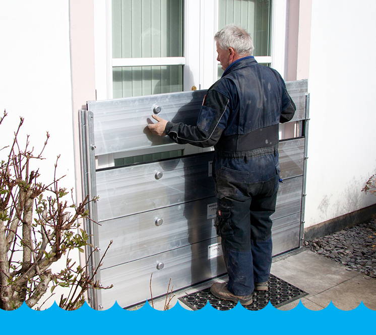 A person attaching a WaterDoor to a person's home to stop the home from flooding. 