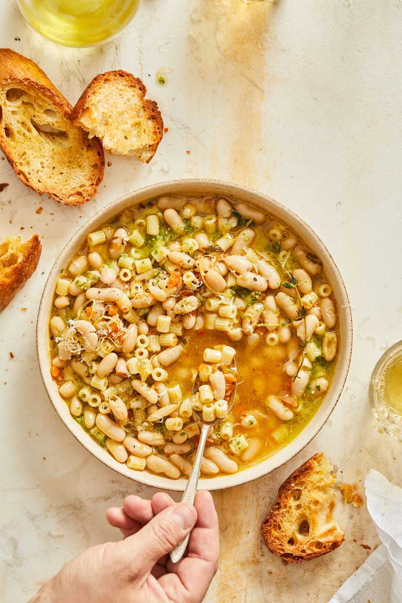 A brothy soup with ditaliani, cannellini beans, and basil pesto.
