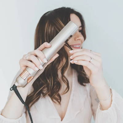 brown lowlight haired woman using all in one curling iron 