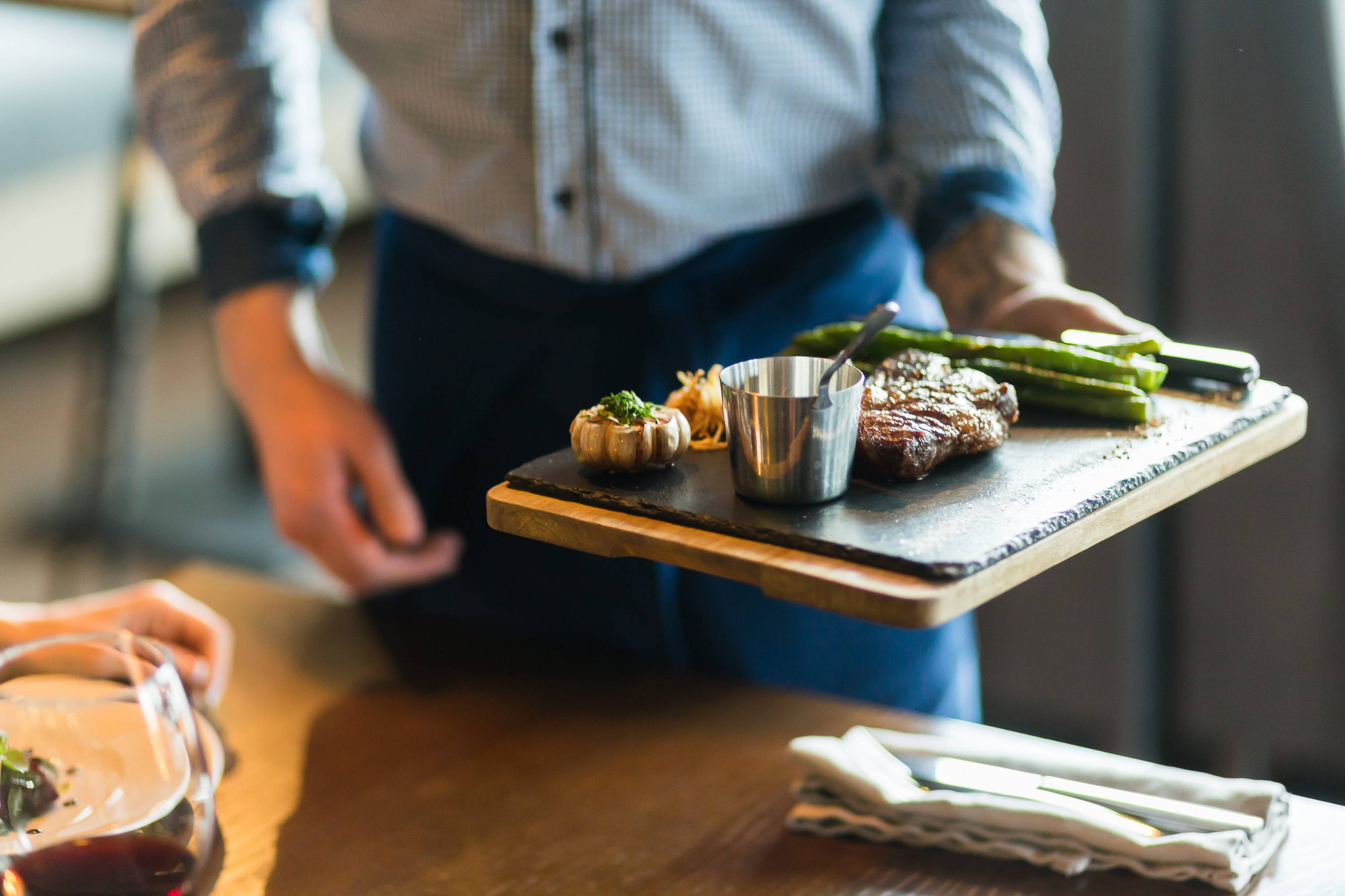 Server in sharp uniform serves beautifully plated dish on slate board