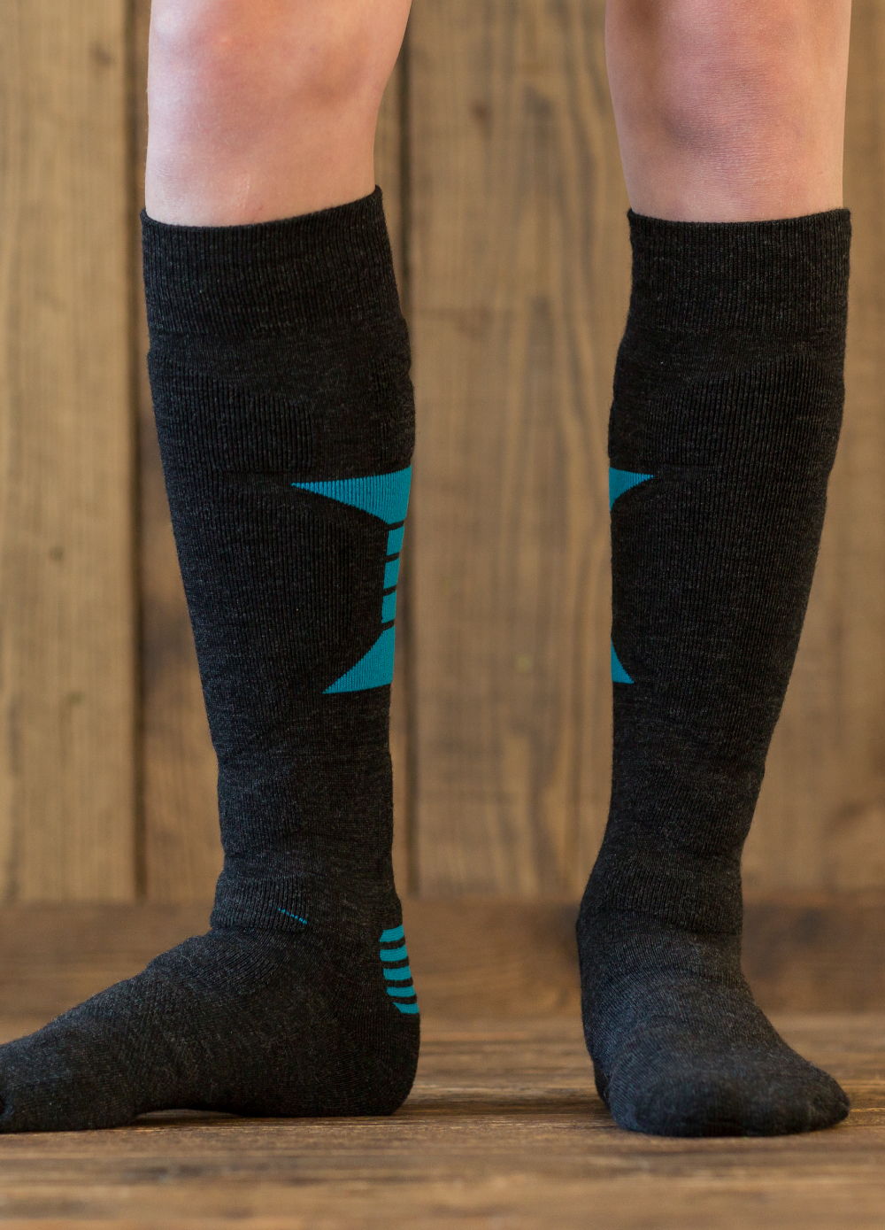 Person wearing knee-high black socks with blue accents standing on wooden floor.