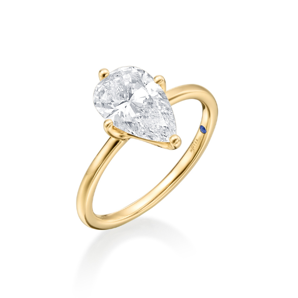 Gold ring with a pear-shaped diamond and a small blue accent.
