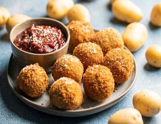 Plate of crispy potato balls with dipping sauce.