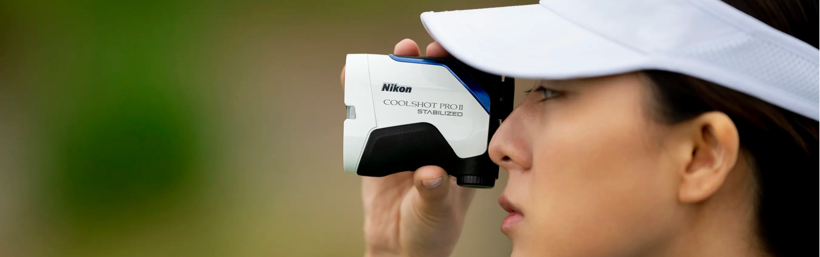 A golfer looking through her Nikon COOLSHOT PROII STABILIZED golf laser rangefinder with slope