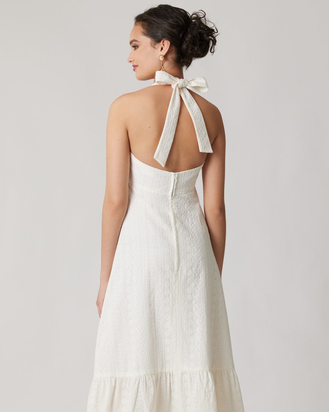 Woman wearing a white dress with a bow at the back.