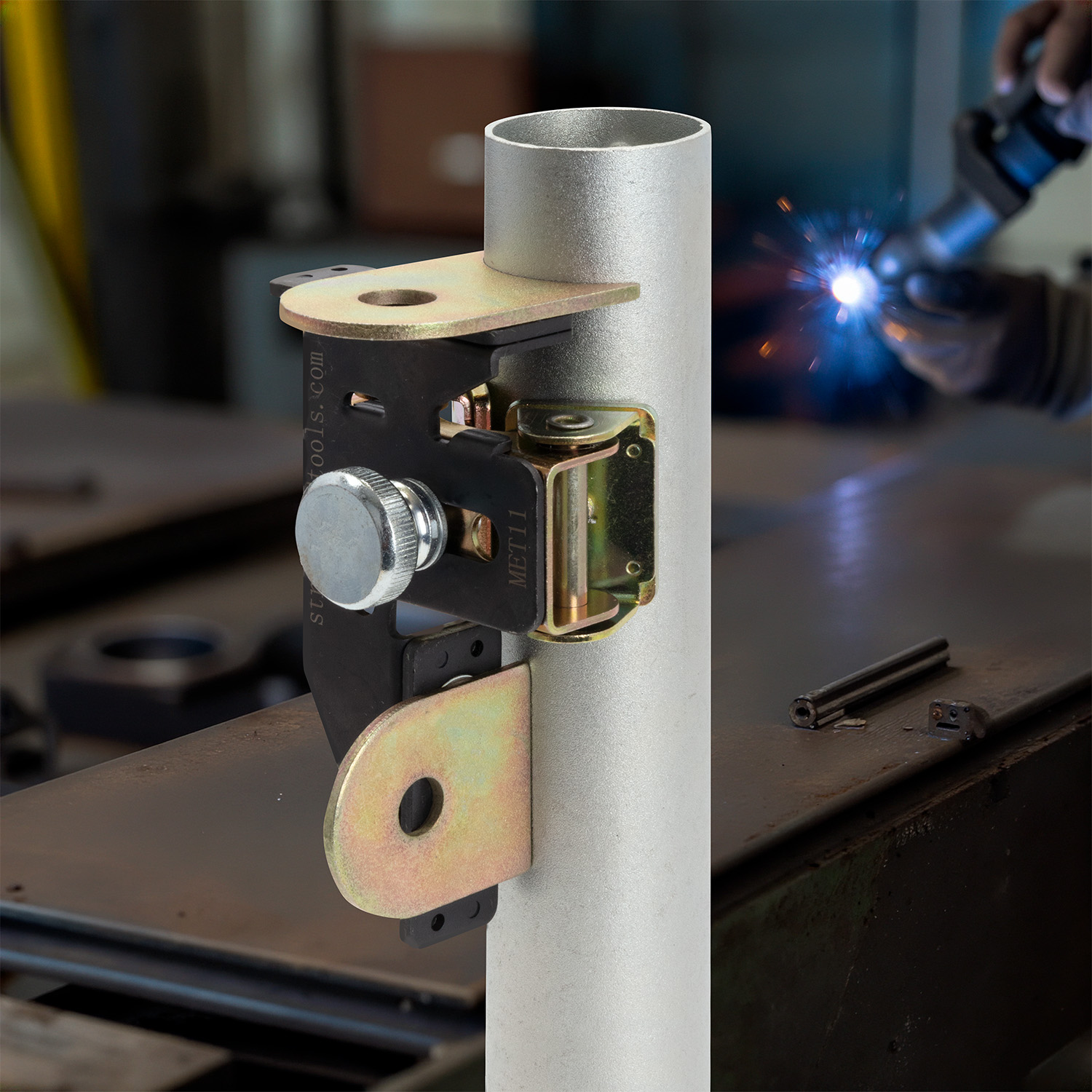 Metal bracket attached to a white pipe in a workshop setting.