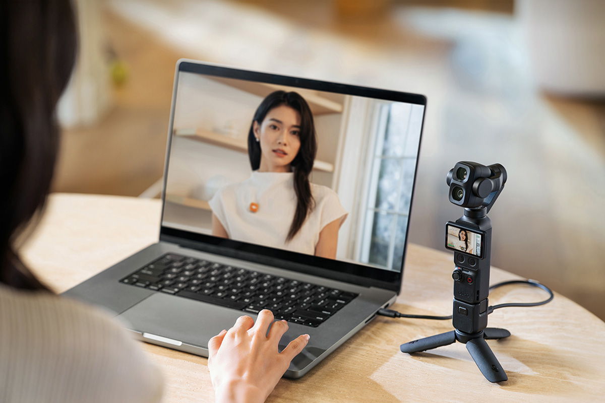 Person on laptop video call with an Osmo Pocket 4P camera setup on desk.