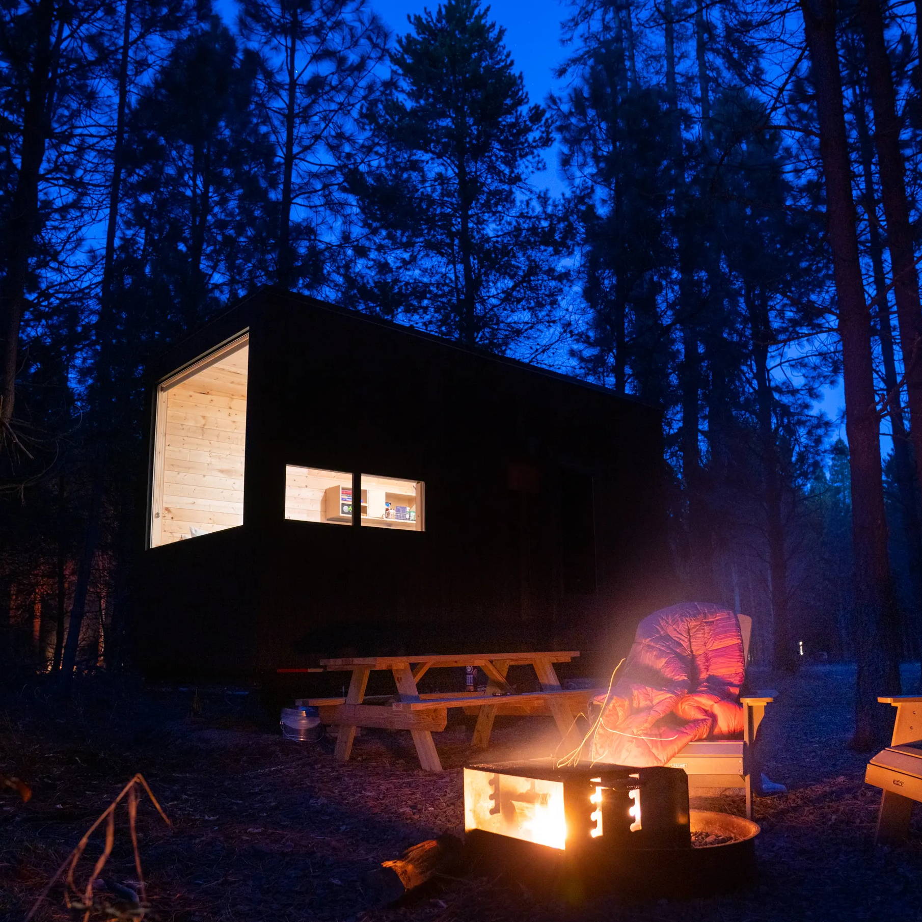 Getaway cabin at night with a campfire and Rumpl blanket