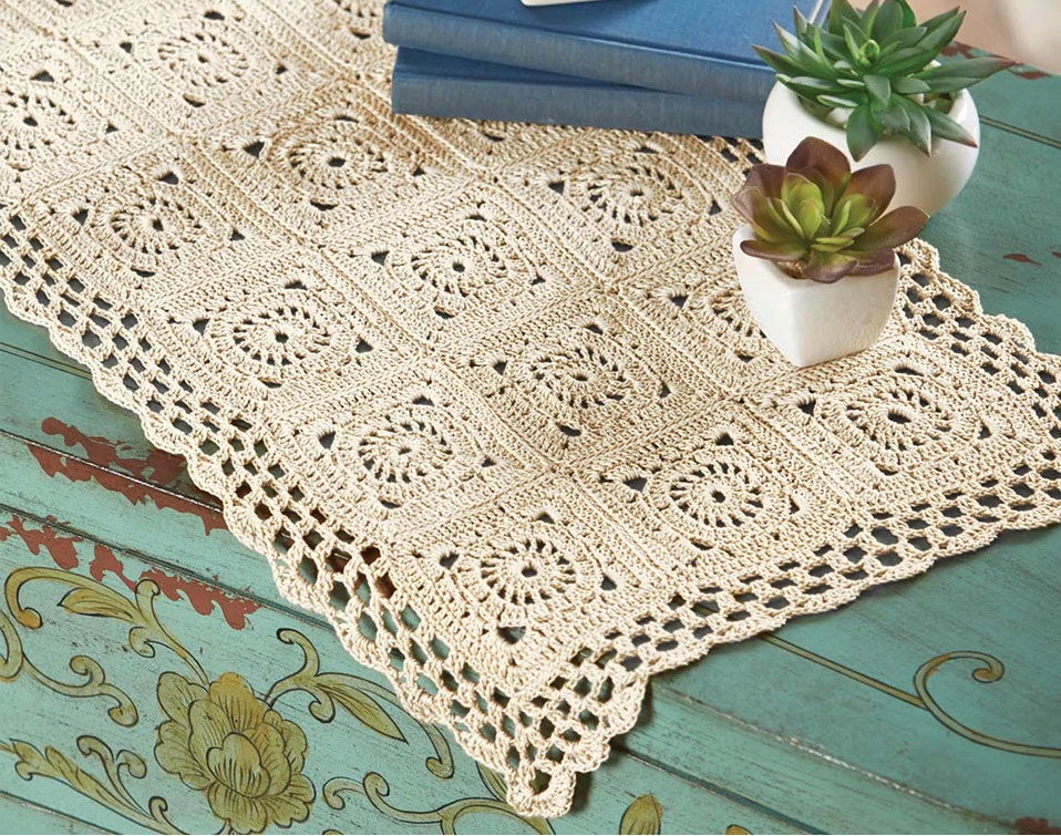 Lace table runner with potted succulents on a wooden surface.