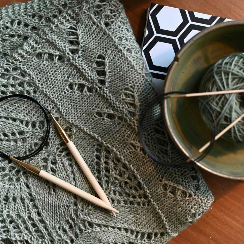 Strickstück mit aufwendigen Mustern auf dem eine Stricknadel liegt.