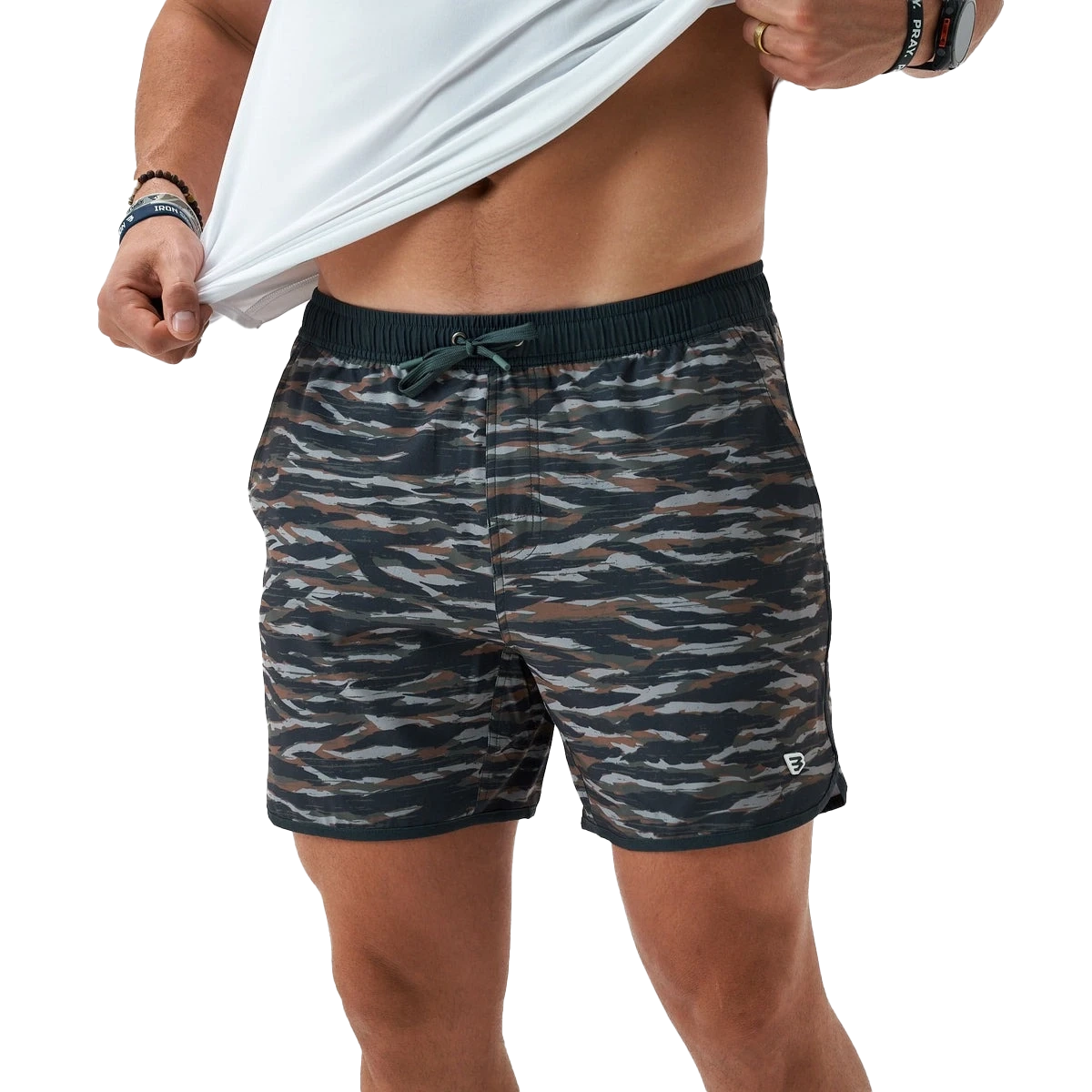 Man lifting a shirt, wearing patterned swim shorts.