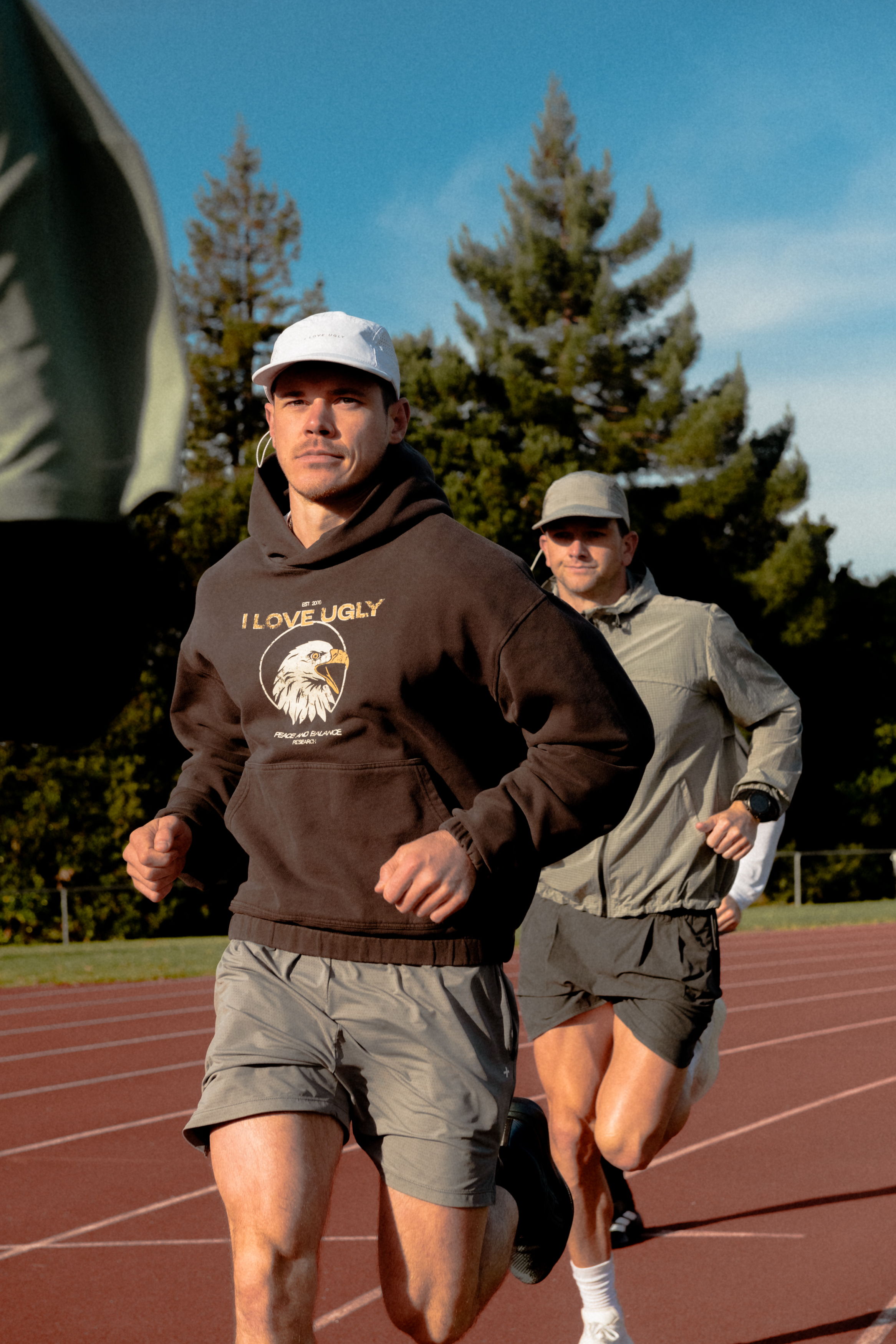 Two men running on a track with trees in the background.