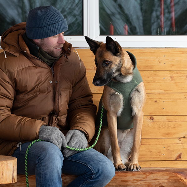 Man sitting with a dog on a wooden bench.
