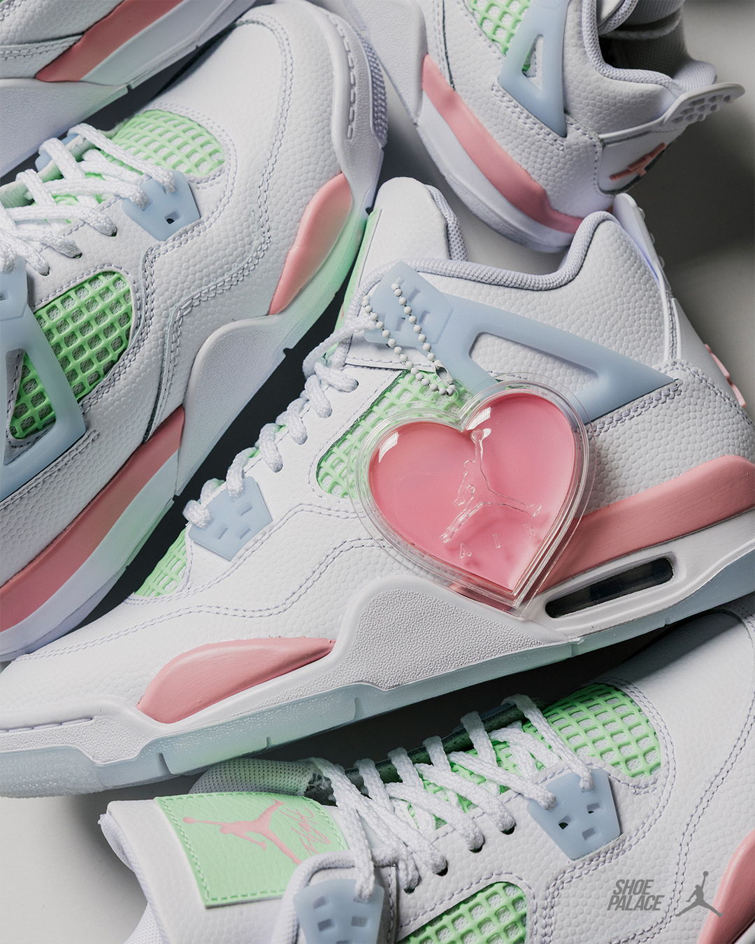 A pair of white sneakers with pastel accents and a heart-shaped accessory.