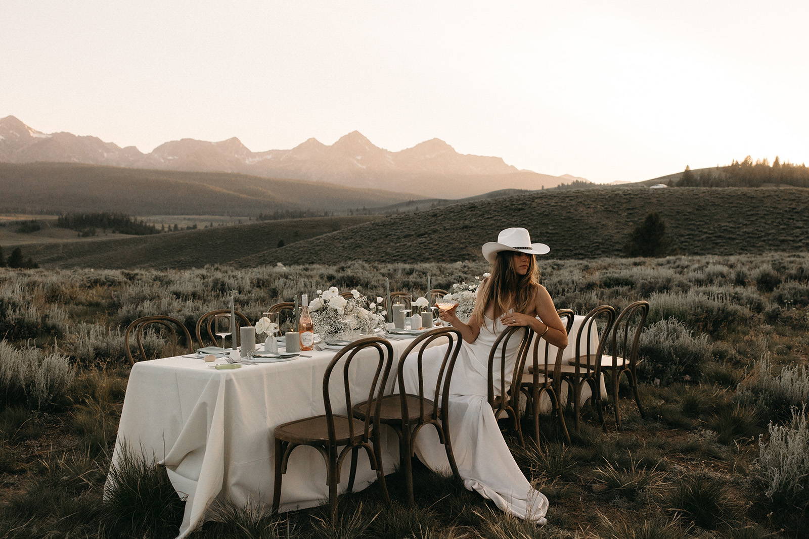 Bride sitting at the reception table in her cowboy hat
