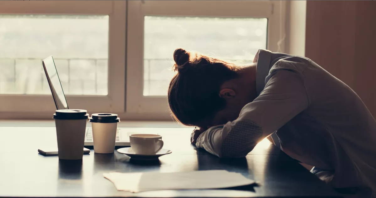 image of a woman, tired, on her desk