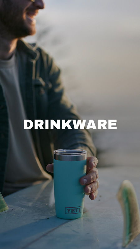 A person holding a blue YETI drinkware against a scenic background.