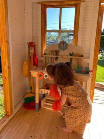 One kid playing inside a wooden playhouse by WholeWoodPlayhouses