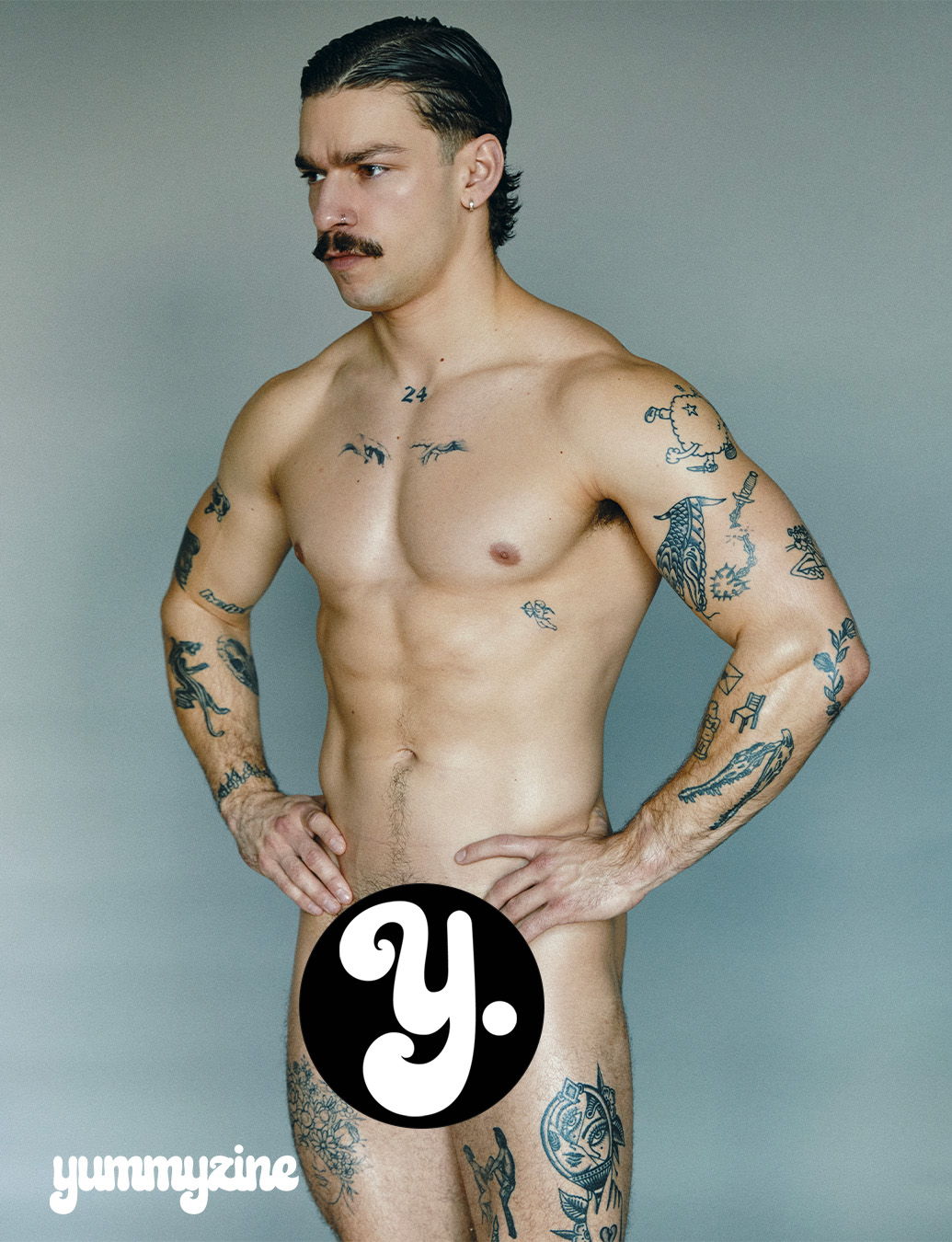 Man with tattoos posing, partially covered by a logo.