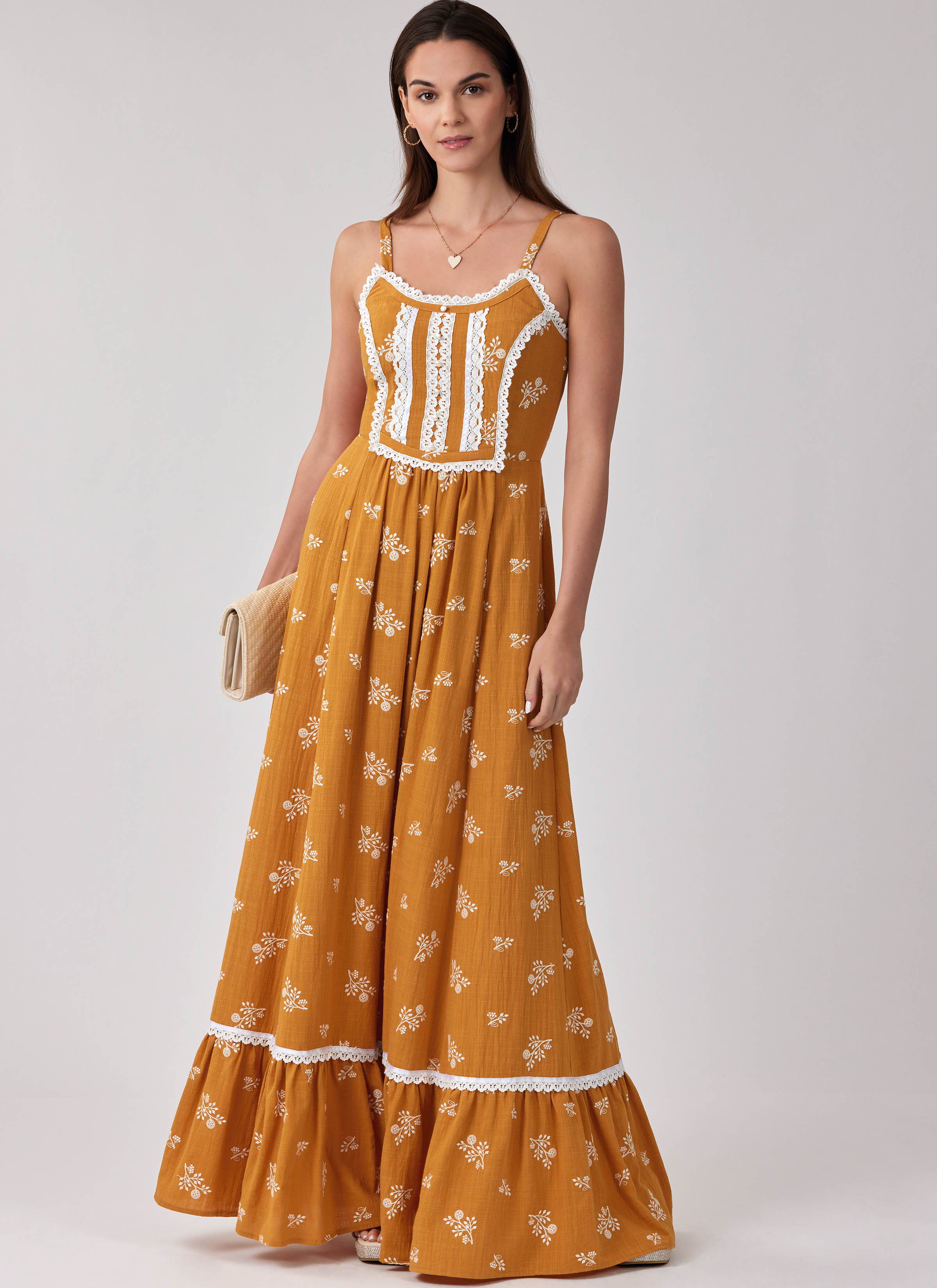 Woman wearing a long, mustard-colored floral dress with a tiered hem.