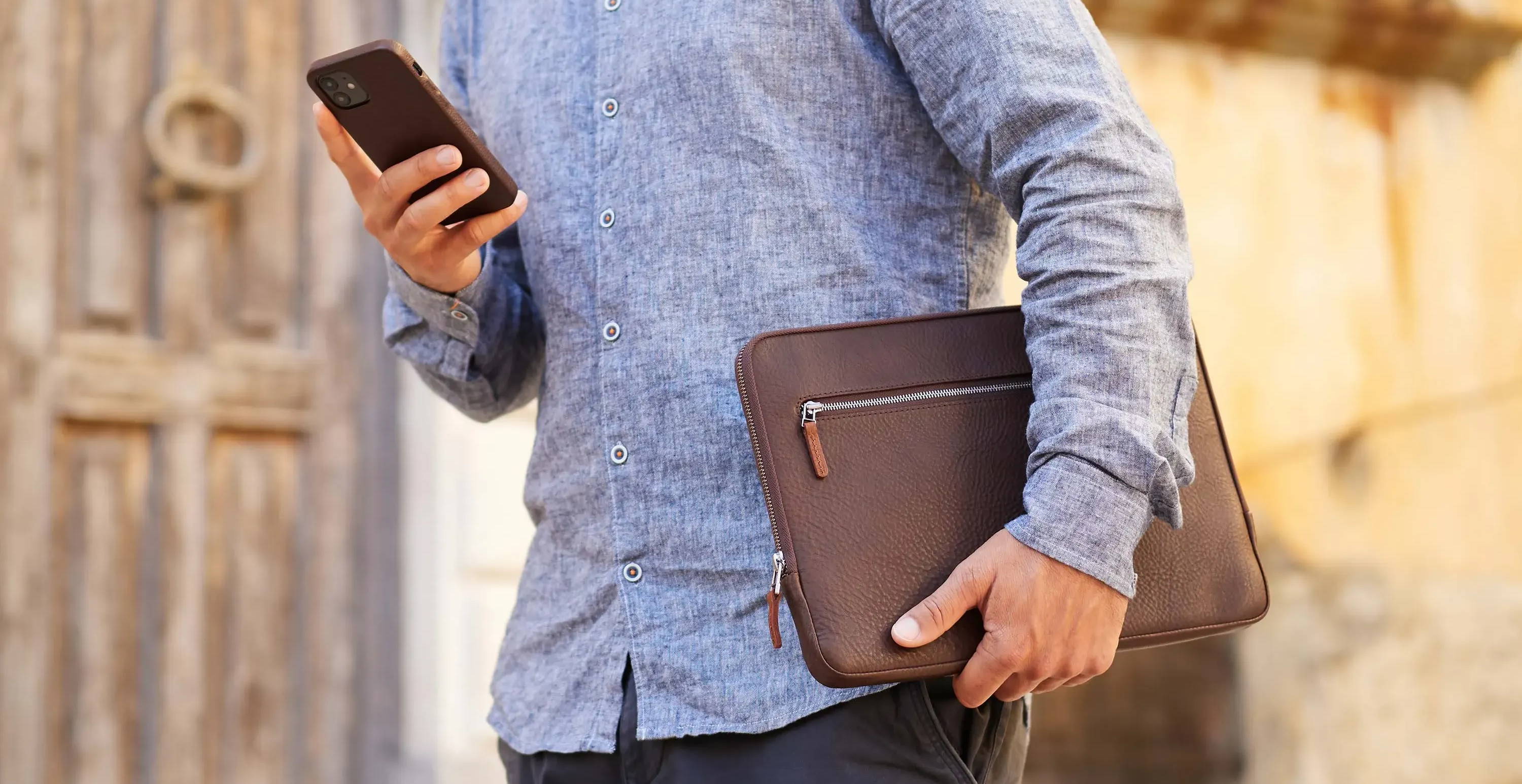 Ein Mann trägt ein Macbook Hülle aus Leder von GoodWilhelm in der Farbe Chocolate