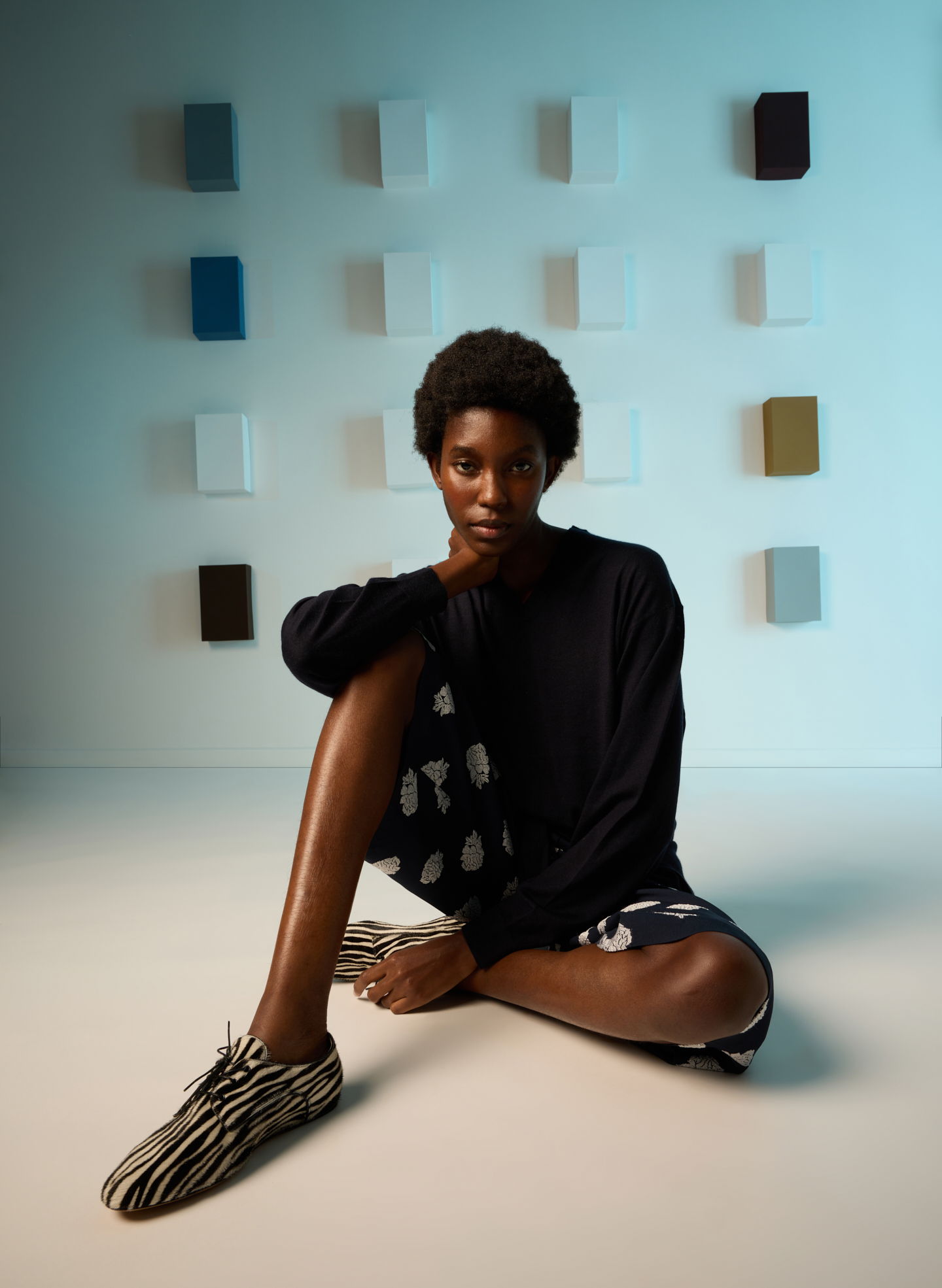 A woman sitting on the floor with a colorful background.