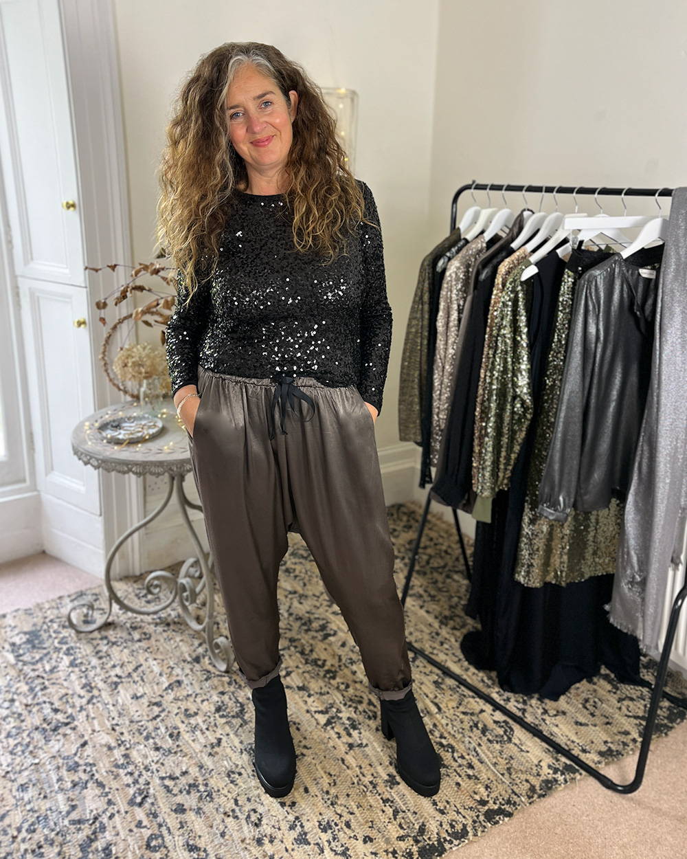 Emma wearing a black sequinned top and grey satin trousers
