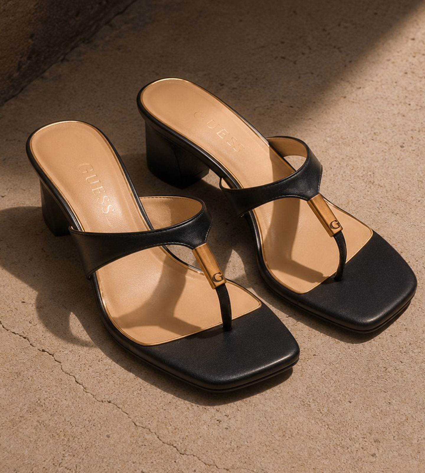Black heeled sandals with a minimalist design on a concrete surface.