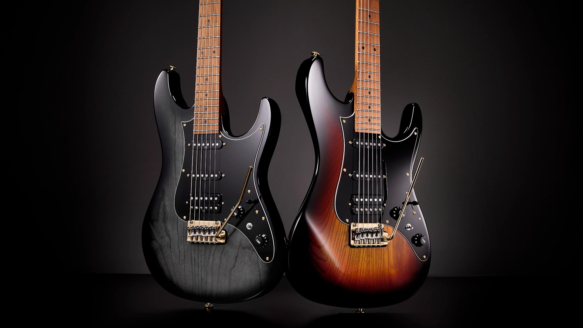 Two Ibanez AZ Series Prestige electric guitars on a dark background.
