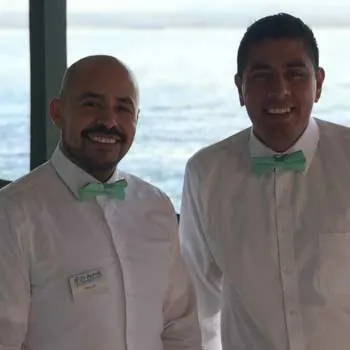Two waiters wearing a seafoam bow tie.