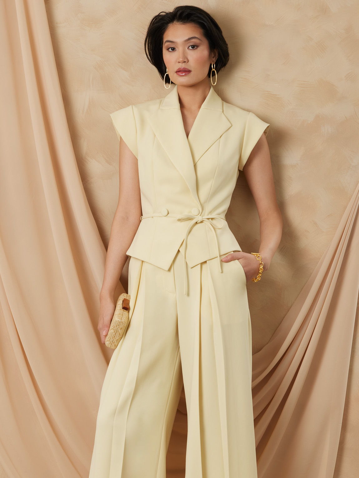 Woman in a stylish yellow suit against a soft beige background.