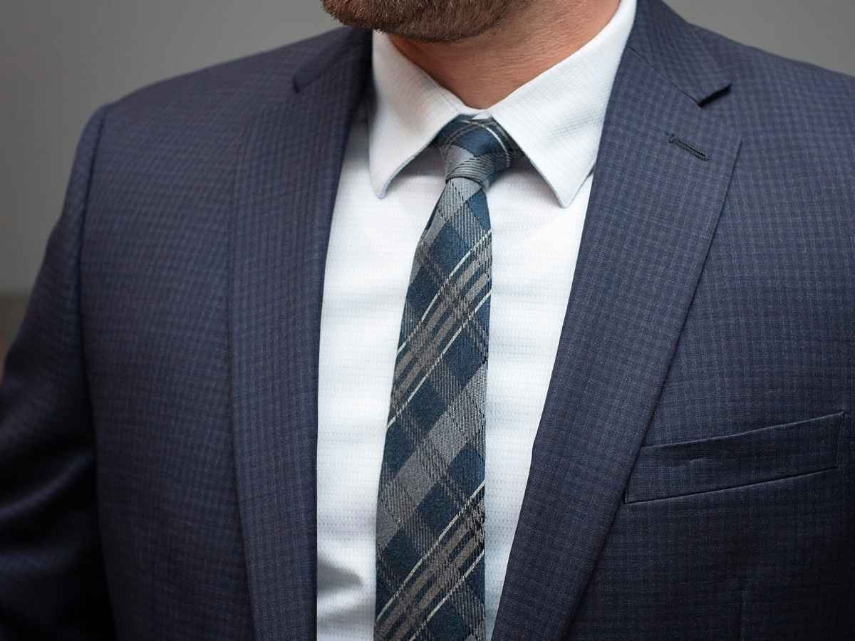 Man wearing a textured plaid wool tie in blue and gray with a navy suit jacket
