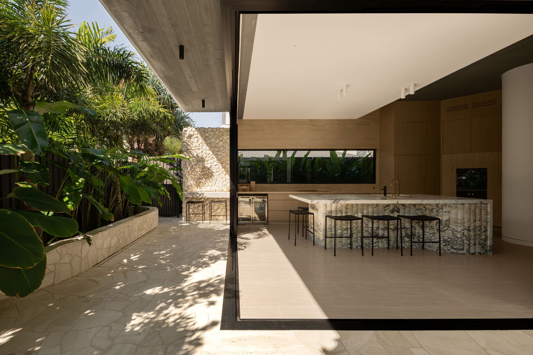 Modern kitchen blending into greenery and outdoor space.