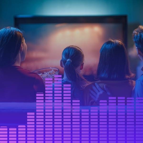 People watching a movie with a colorful soundwave graphic overlay.