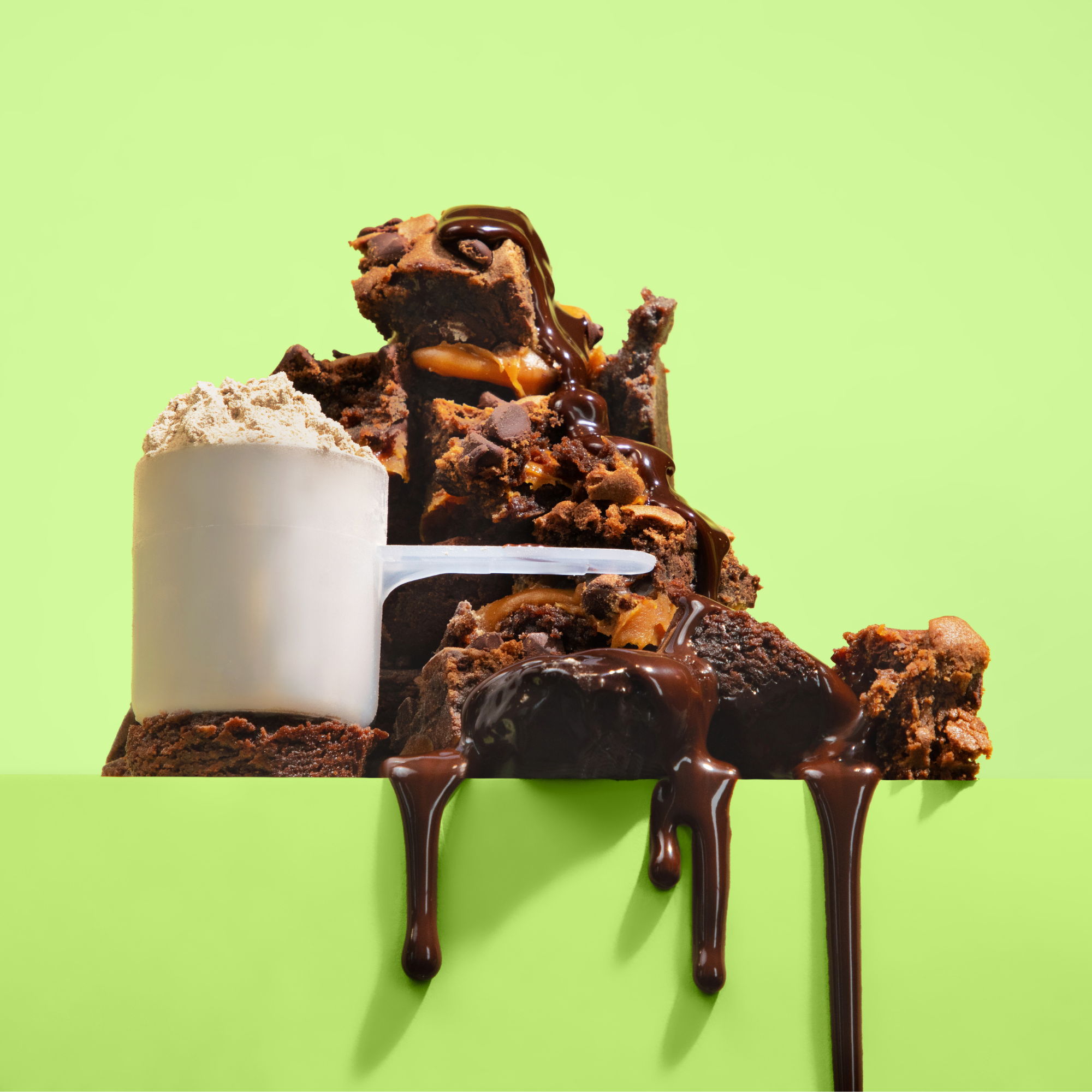 Scoop of protein powder beside stacked fudgy chocolate brownies with rich chocolate drizzle on a bright green background.