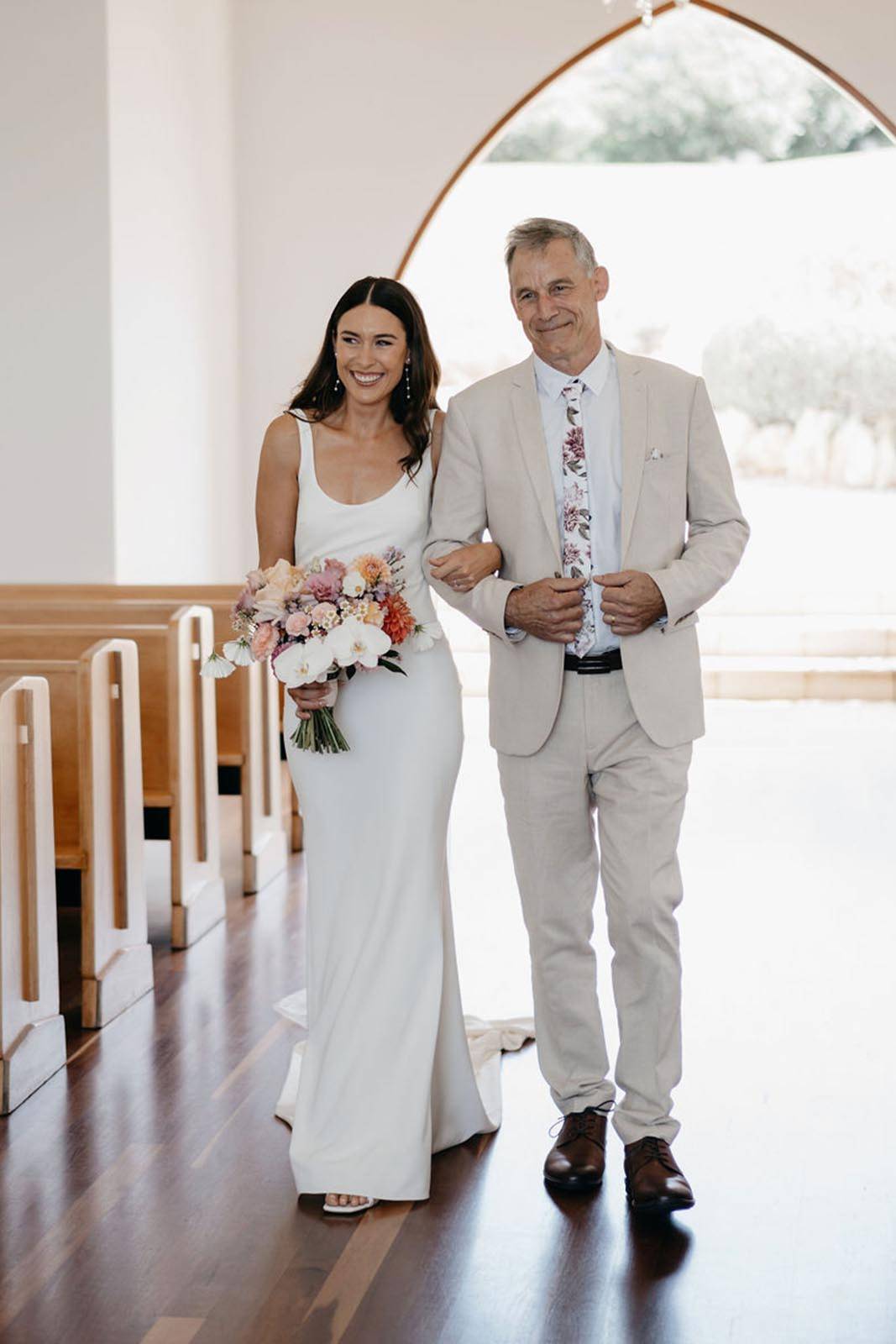 Emotional moment captured as the bride walks down the aisle, arm in arm with her father.