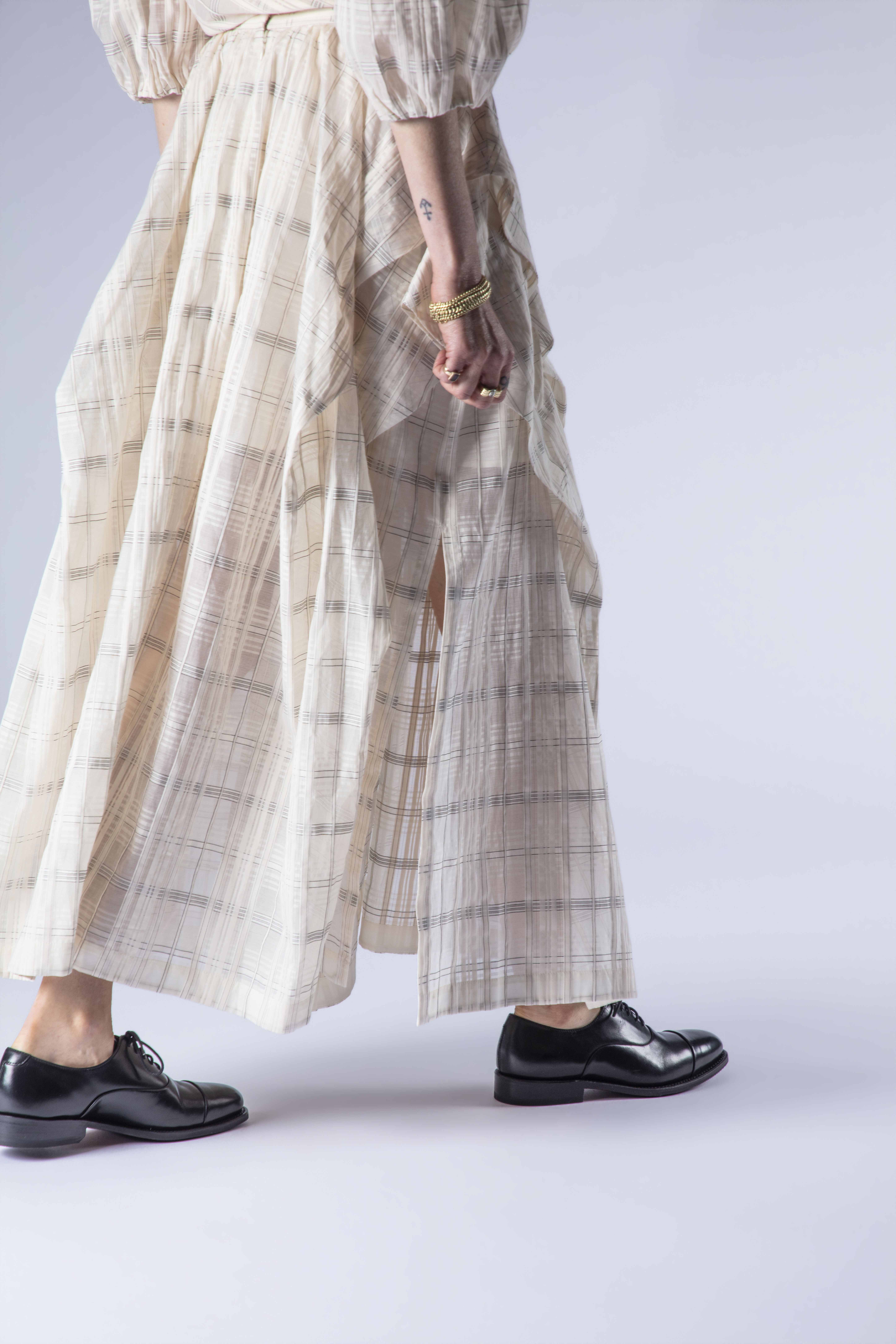 A person in a long, flowing skirt and black shoes.
