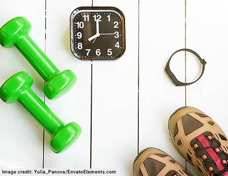 light green dumbells, black and white clock, smart watch, and tan and red sneakers on light wood background